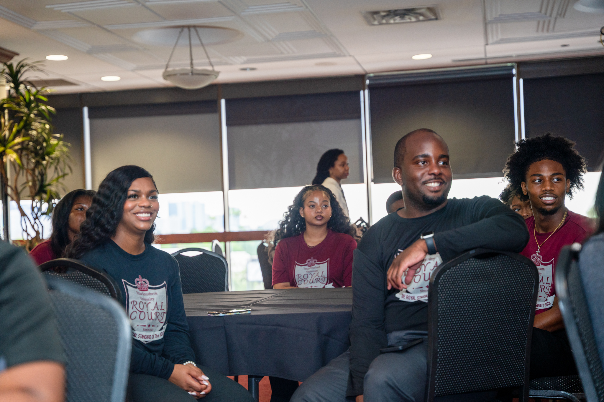 Image of students looking to the side, the reflection of a screen on a dark classroom.